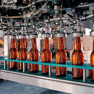 Nápojové fľaše sa presúvajú cez výrobňu nápojov. Monitorovanie tvrdosti vody je dôležité na zachovanie kvality produktu.